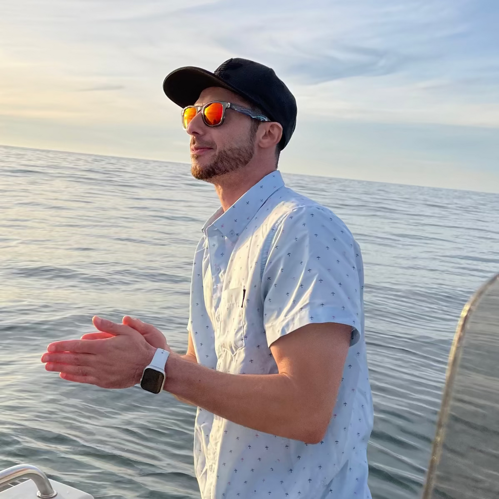 A person on a boat in the ocean with a sunset or sunrise sky.